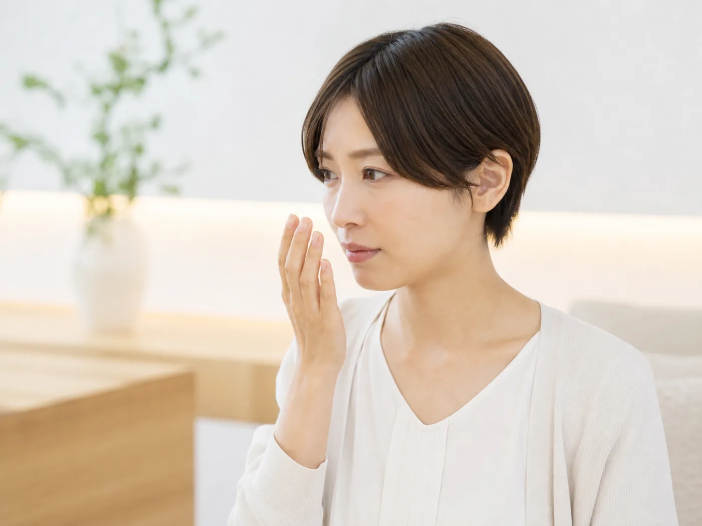 手を口元に当てて息を気にする女性