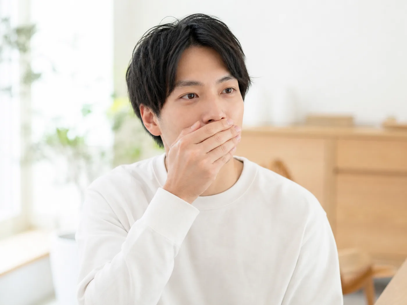 口元を手で覆って驚く男性